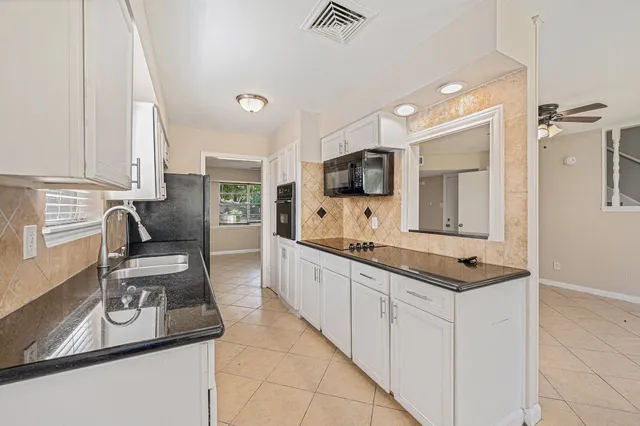 a kitchen with granite countertop a sink and white cabinets