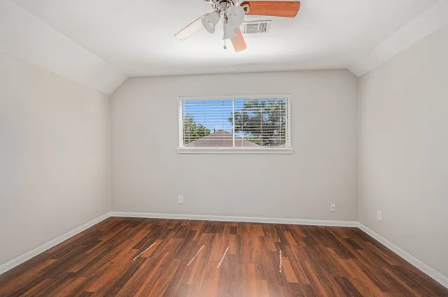 an empty room with a window and wooden floor