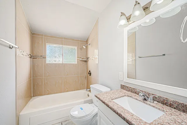 a bathroom with a granite countertop tub sink toilet a mirror a vanity and shower