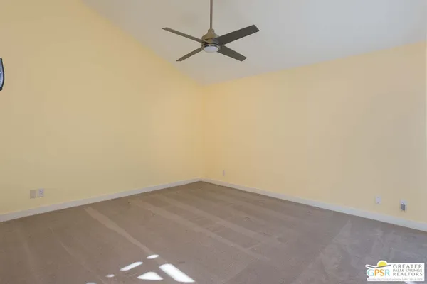 an empty room with a ceiling fan and carpet