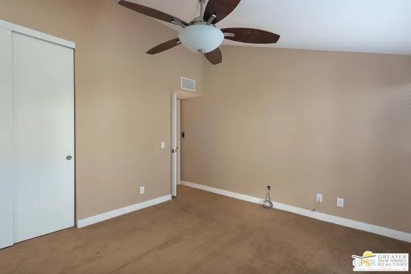 an empty room with closet and fan