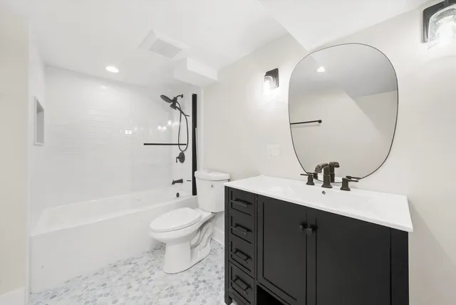 a bathroom with a toilet a sink a mirror and a bathtub