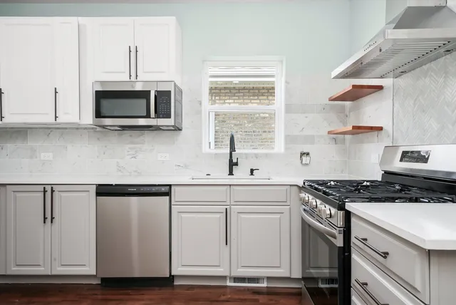 a kitchen with stainless steel appliances granite countertop a sink a stove and a microwave