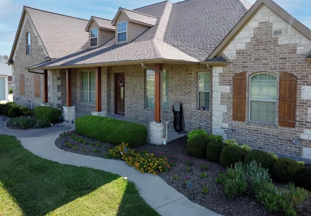 a view of a brick house with a yard potted plants and a table