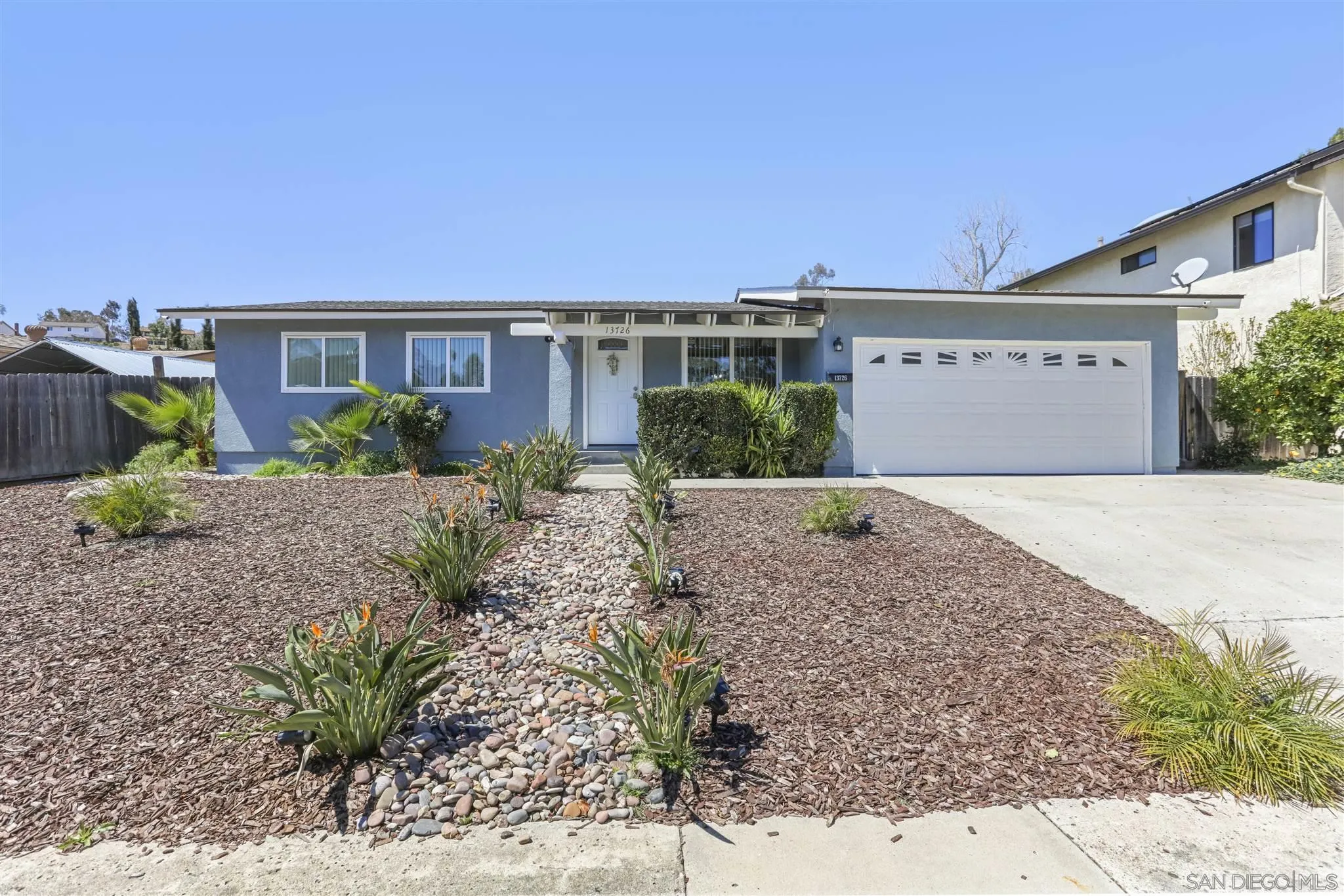a front view of a house with a yard and potted plants