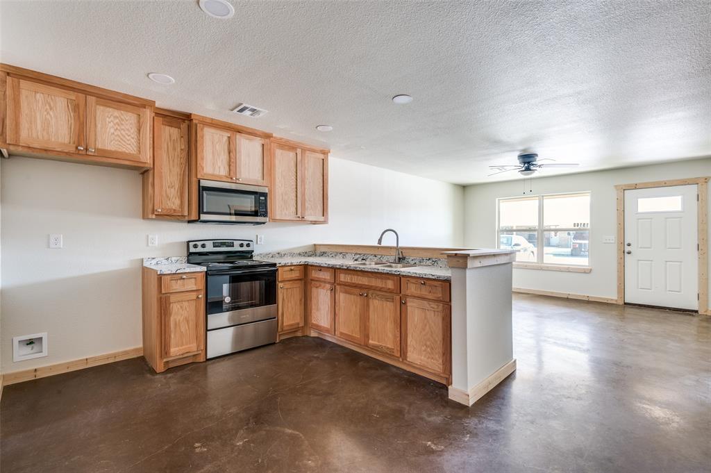 19161 Cabo Way, Unit 19171 Thackerville, OK 73459 - Photo 8 of 18 a kitchen with stainless steel appliances kitchen island granite countertop a stove a sink and a microwave