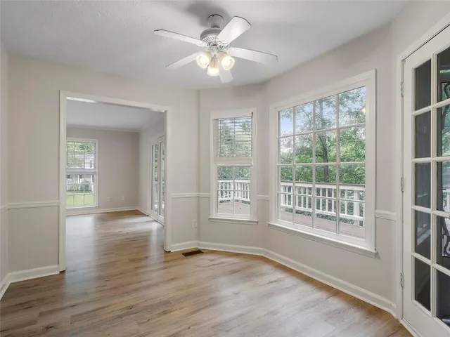 a view of an empty room with a window and wooden floor