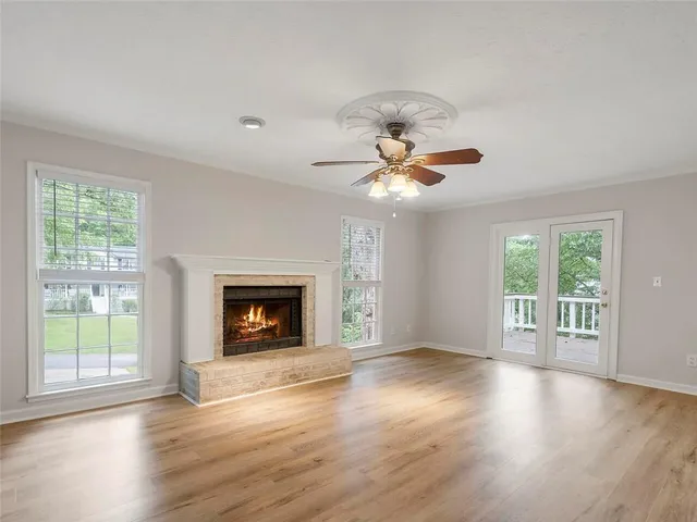 a view of an empty room with wooden floor fireplace and a window