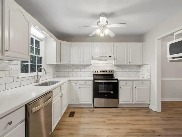 a kitchen with a sink cabinets stainless steel appliances and a window