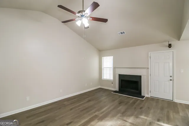 an empty room with fan and fireplace