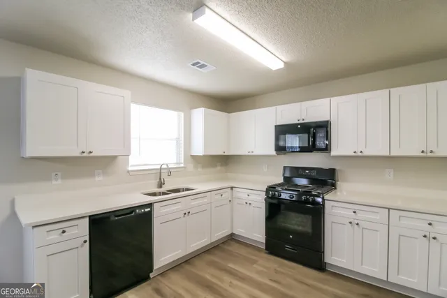 a kitchen with white cabinets and appliances