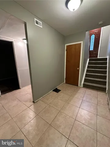 a view of an empty room with wooden floor and stairs