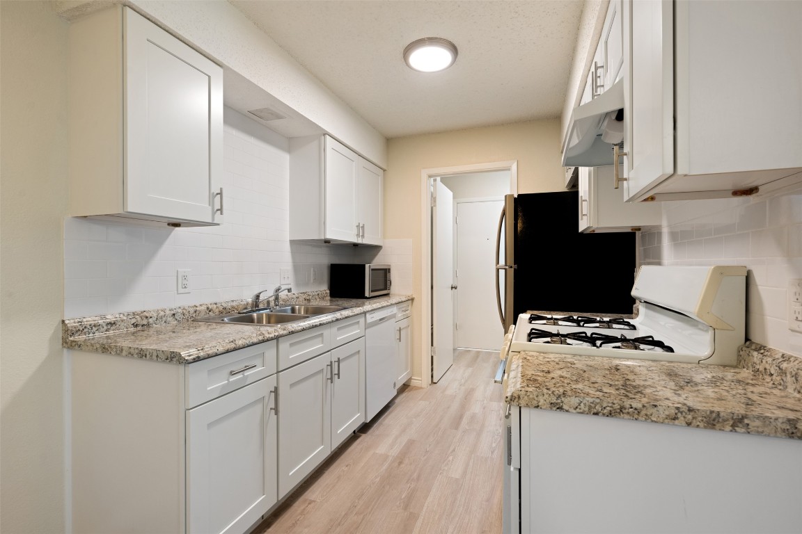 608 Country Aire Drive, Unit A Round Rock, TX 78664 - Photo 13 of 32 a kitchen with stainless steel appliances granite countertop a stove top oven a sink a refrigerator and white cabinets