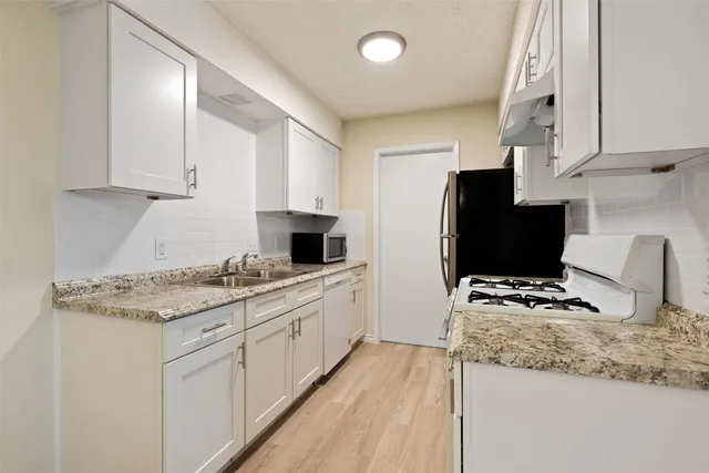 a kitchen with granite countertop a sink stove and refrigerator