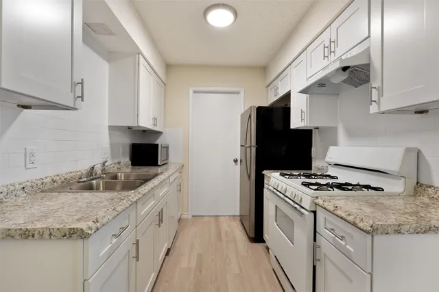 a kitchen with granite countertop stainless steel appliances a sink stove and refrigerator