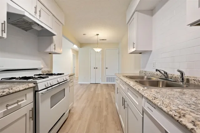a kitchen with granite countertop a sink cabinets and stainless steel appliances
