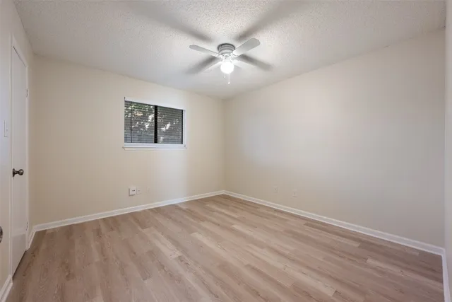 an empty room with a ceiling fan and window