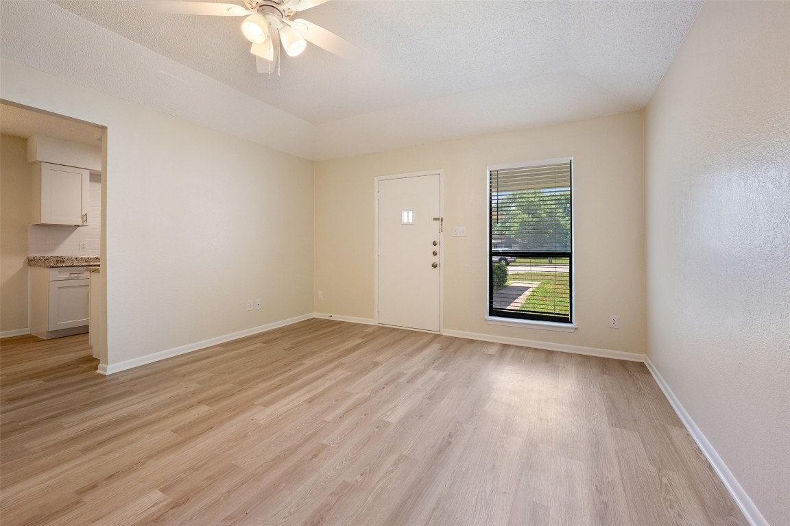 608 Country Aire Drive, Unit A Round Rock, TX 78664 - Photo 7 of 32 an empty room with wooden floor a ceiling fan and windows