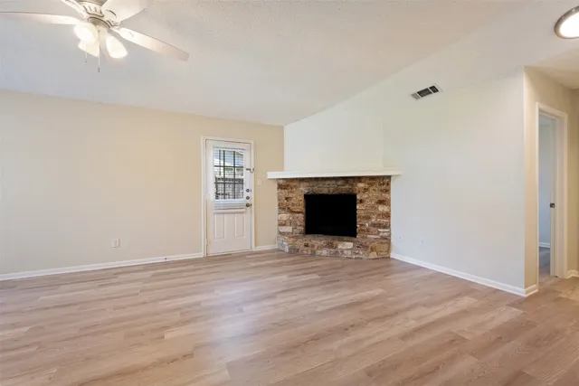 a view of empty room with wooden floor and fireplace