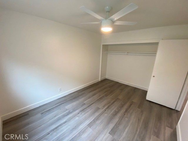 an empty room with wooden floor and fan