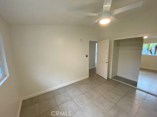 an empty room with a bathroom and chandelier fan