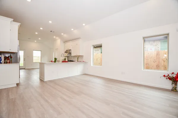 a view of a kitchen with kitchen island wooden floors and stainless steel appliances