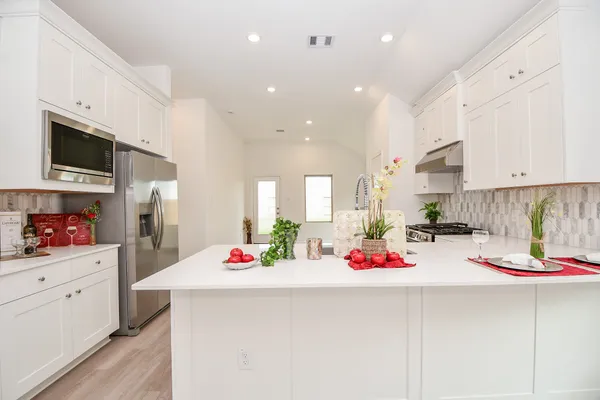 a kitchen with white cabinets and appliances