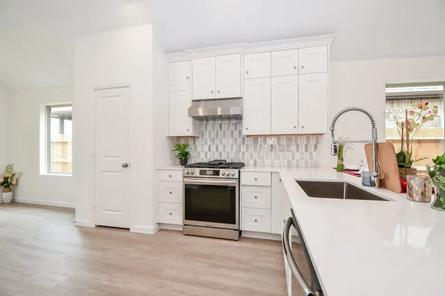 a kitchen with granite countertop white cabinets and stainless steel appliances