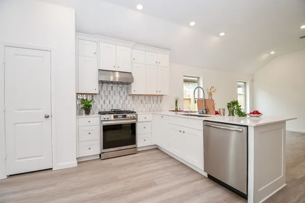 a kitchen with granite countertop white cabinets and stainless steel appliances