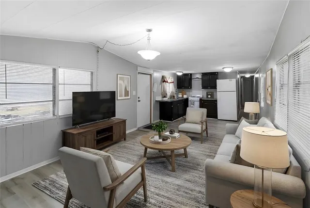 a living room with furniture a flat screen tv and kitchen view