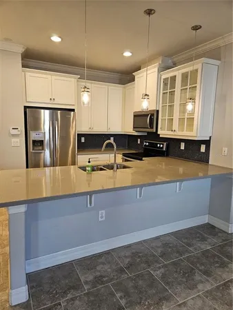 a kitchen with kitchen island granite countertop a sink a counter top space appliances and cabinets