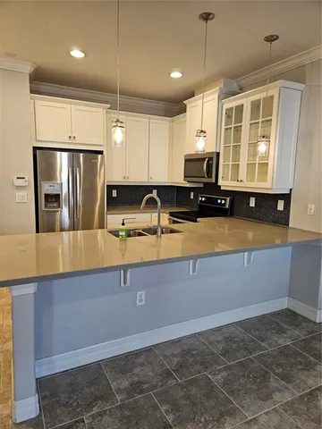 a kitchen with kitchen island granite countertop a sink a counter top space appliances and cabinets