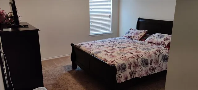 a bed sitting in a bedroom next to a window with lamp