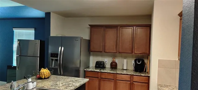 a kitchen with stainless steel appliances granite countertop a refrigerator and a stove top oven