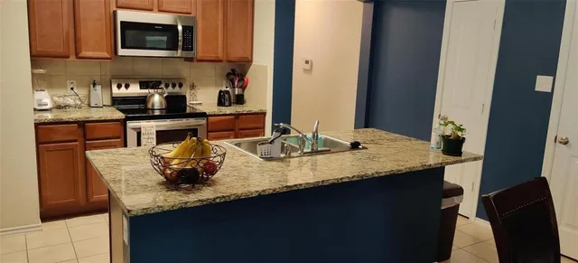 a kitchen with granite countertop stainless steel appliances a sink stove and microwave