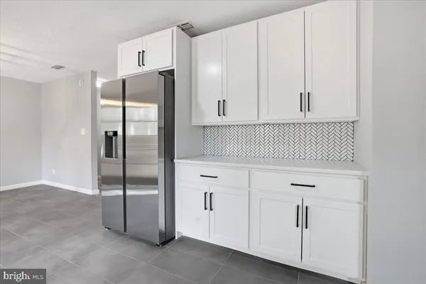a kitchen with white cabinets and refrigerator