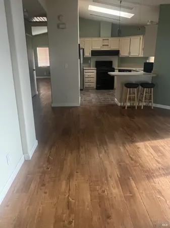 an empty room with wooden floor a fireplace and windows