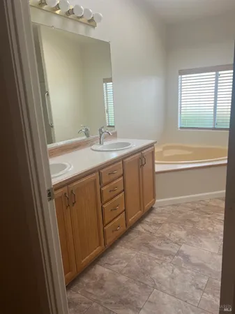 a spacious bathroom with a tub sink and mirror