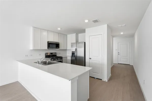 a kitchen with a sink a refrigerator a microwave and cabinets