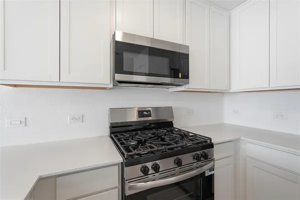 a kitchen with microwave cabinets and stove top oven