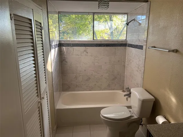 a bathroom with a bathtub toilet and window