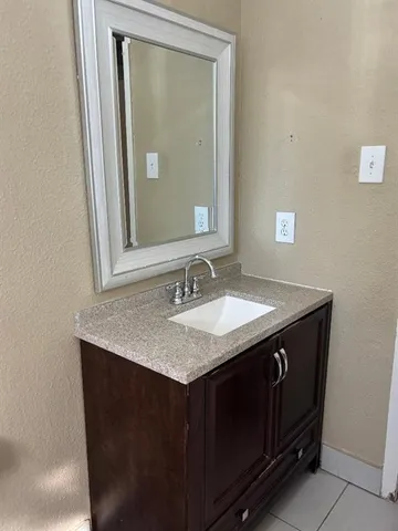 a bathroom with a granite countertop sink vanity and mirror