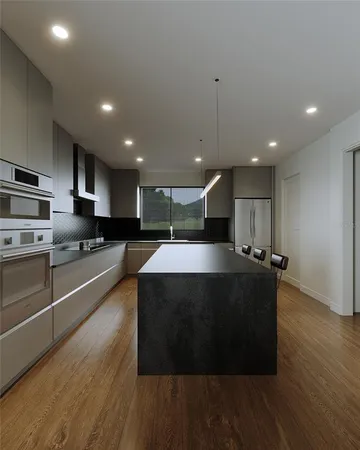 a large kitchen with stainless steel appliances a large counter top a stove a sink dishwasher and a refrigerator with wooden floor