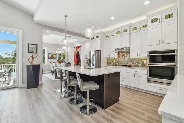 a kitchen with stainless steel appliances kitchen island granite countertop a table chairs and a refrigerator