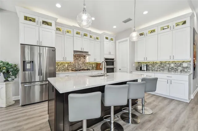a kitchen with stainless steel appliances granite countertop a table chairs stove and refrigerator
