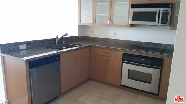 a kitchen with granite countertop a stove top oven microwave and cabinets