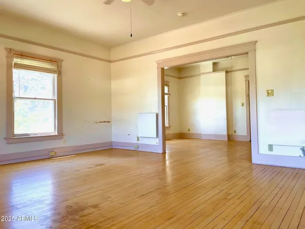 a view of an empty room with window and wooden floor
