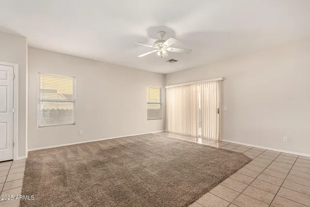 an empty room with chandelier fan and windows