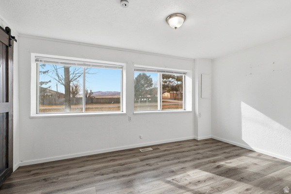 25615 Main Street Portage, UT 84331 - Photo 15 of 42 Empty room featuring a barn door and wood finished floors