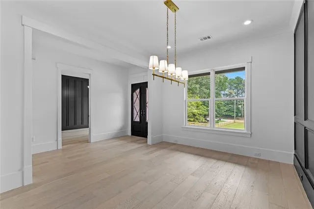 a view of an empty room with window and wooden floor